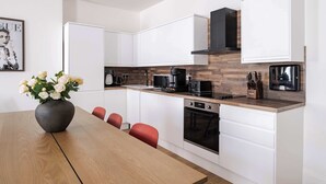 A modern kitchen with white cabinets, a wooden countertop, a black coffee maker, and a vase of white flowers on the table. - Stunning 2BR 2BA in the ♥️ of Marylebone ❄️ Air Conditioning | Sleeps 8 (Greater London)