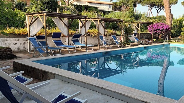 A swimming pool with lounge chairs and a pergola structure. - The Vineyard (Forio)