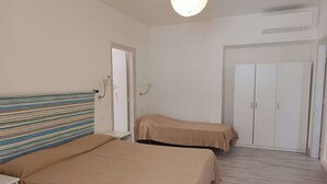A bedroom with two beds, a wardrobe, and a small table. - The Vineyard (Forio)
