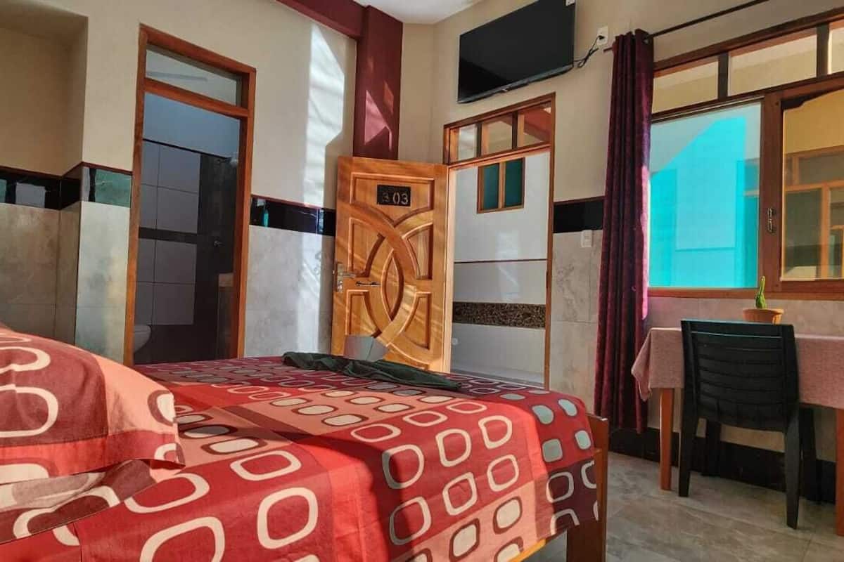A room with a bed, a desk, and a window with curtains.