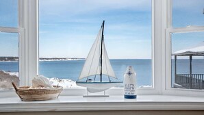 A model sailboat on a windowsill with a view of the ocean and a bottle with coordinates. - Oceanfront Views, 2 Living Rooms, Walk to Beach (York)