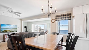 A dining area with a wooden table and chairs, a chandelier, and a view of the ocean through large windows. - Oceanfront Views, 2 Living Rooms, Walk to Beach (York)