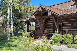 A log cabin with a porch, surrounded by a garden with various plants and flowers. - Outpost: Golf and Tennis Cabin 5870 - Close to Nat'l Park (Jackson)