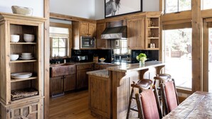 Una cocina rústica con armarios de madera, una isla central y un comedor con sillas.