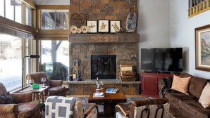 Un salón acogedor con chimenea de piedra, televisor de pantalla plana y asientos cómodos.