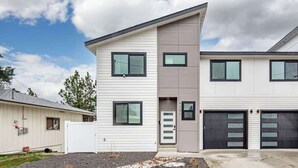A modern two-story house with a garage, a driveway, and a small garden area. - River Ridge Villa- New Build! (Spokane)