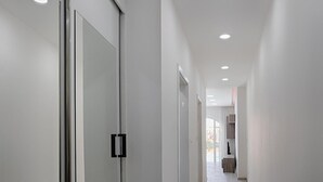 A hallway with a glass door, a wooden bench, and a view of the outside. - Seafront Designer Bliss in Central St Julian's (St. Julian's)