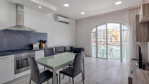 A modern kitchen with a dining area, a large window with a view of the city, and a built-in oven. - Seafront Designer Bliss in Central St Julian's (St. Julian's)