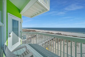 A balcony with a view of the beach and ocean.