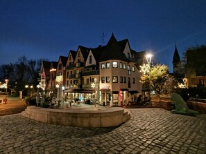 Een historisch gebouw met meerdere verdiepingen, een binnentuin met een fontein en een geplaveid erf.