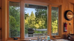 Una cocina con un lavamanos, una ventana con vista a una terraza que tiene una parrilla, y un extintor de incendios en la pared.