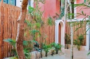 Escape to a serene oasis amidst lush tropical plants and palm trees, surrounded by a bamboo fence and a modern architectural design.