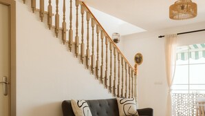 Ein modernes Wohnzimmer mit einem dunkelgrauen Sofa, einem kleinen Holztisch und einer Treppe mit Holzwand.