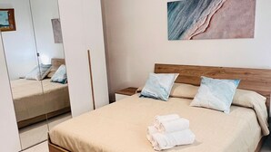 A bedroom with a wooden bed, a large mirror, a painting on the wall, and a hanging light fixture. - Casa rita - beach house with garden and bbq grill (Sant'Andrea Apostolo Dello Ionio Marina)