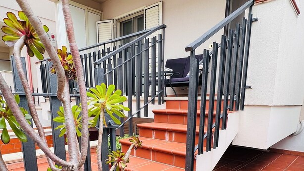 A residential building with a staircase leading to a balcony, surrounded by greenery and a tiled floor. - Casa rita - beach house with garden and bbq grill (Sant'Andrea Apostolo Dello Ionio Marina)