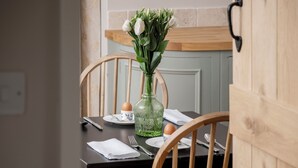 A dining table set with plates, a vase of flowers, and a green bottle.