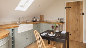 A kitchen with a skylight, a wooden dining table set for two, and a wooden door.