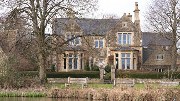 A historic stone building with a pond, ducks, and seagulls.