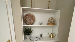 A white built-in shelf unit with decorative items, a small stool, and a door with a brass doorknob.