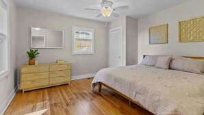 A bedroom with a bed, a dresser, a ceiling fan, and a window with blinds.
