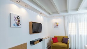 A modern living room with a sofa, a mounted TV, and artwork on the walls. - Standard Triple Studio with Fimestra (Bagheria)