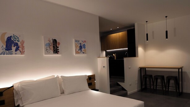 A modern bedroom with a large bed, a wooden headboard, and a desk with stools in the adjacent area. - Standard Triple Studio with Fimestra (Bagheria)