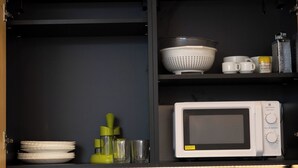 A kitchen with a microwave, a colander, a grater, and stacked plates. - Deluxe Triple Studio with Terrace (Bagheria)