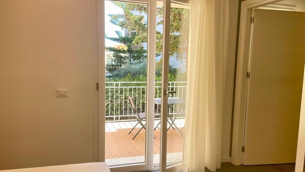 Une pièce dotée d’une porte-fenêtre coulissante donnant sur un balcon extérieur, avec une table et des chaises.
