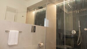 Une salle de bain moderne dotée d’une douche à parois de verre, de toilettes et d’un porte-serviettes.