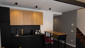 A modern kitchen with black cabinets, a wooden countertop, and a dining area with a wooden table and two chairs. - Deluxe Quadruple Loft Studio with Terrace (Bagheria)