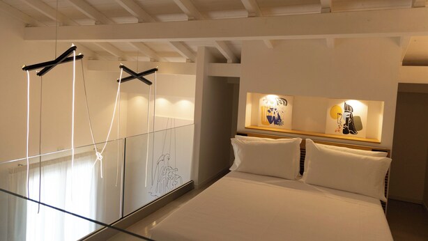 A hotel room with a bed, a glass partition, and artwork on the wall. - Deluxe Quadruple Loft Studio with Terrace (Bagheria)