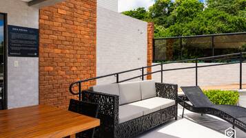 Un espacio exterior con mesa de madera y sofá negro tejido.