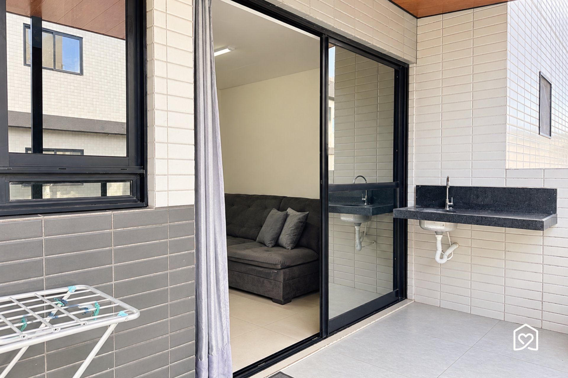 Un baño moderno con mampara de vidrio, lavamanos empotrado y un perchero para toallas.