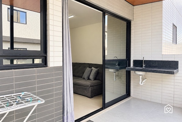 Un baño moderno con mampara de vidrio, lavamanos empotrado y un perchero para toallas.