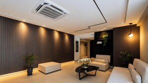 A modern interior with a sofa, a coffee table, and a potted plant. - Mahalo Flat - LikeHome Hospedagens (Joao Pessoa)