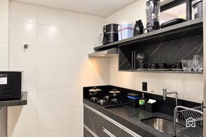 A modern kitchen with a gas stove, black countertops, and a stainless steel sink. - Mahalo Flat - LikeHome Hospedagens (Joao Pessoa)