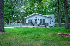 A single-story house with a porch, surrounded by trees and a fenced yard.