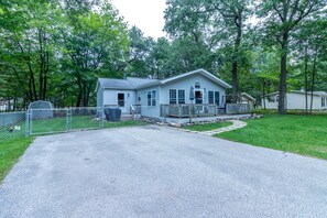 A single-story house with a front porch, a fenced yard, and a driveway leading to the entrance.