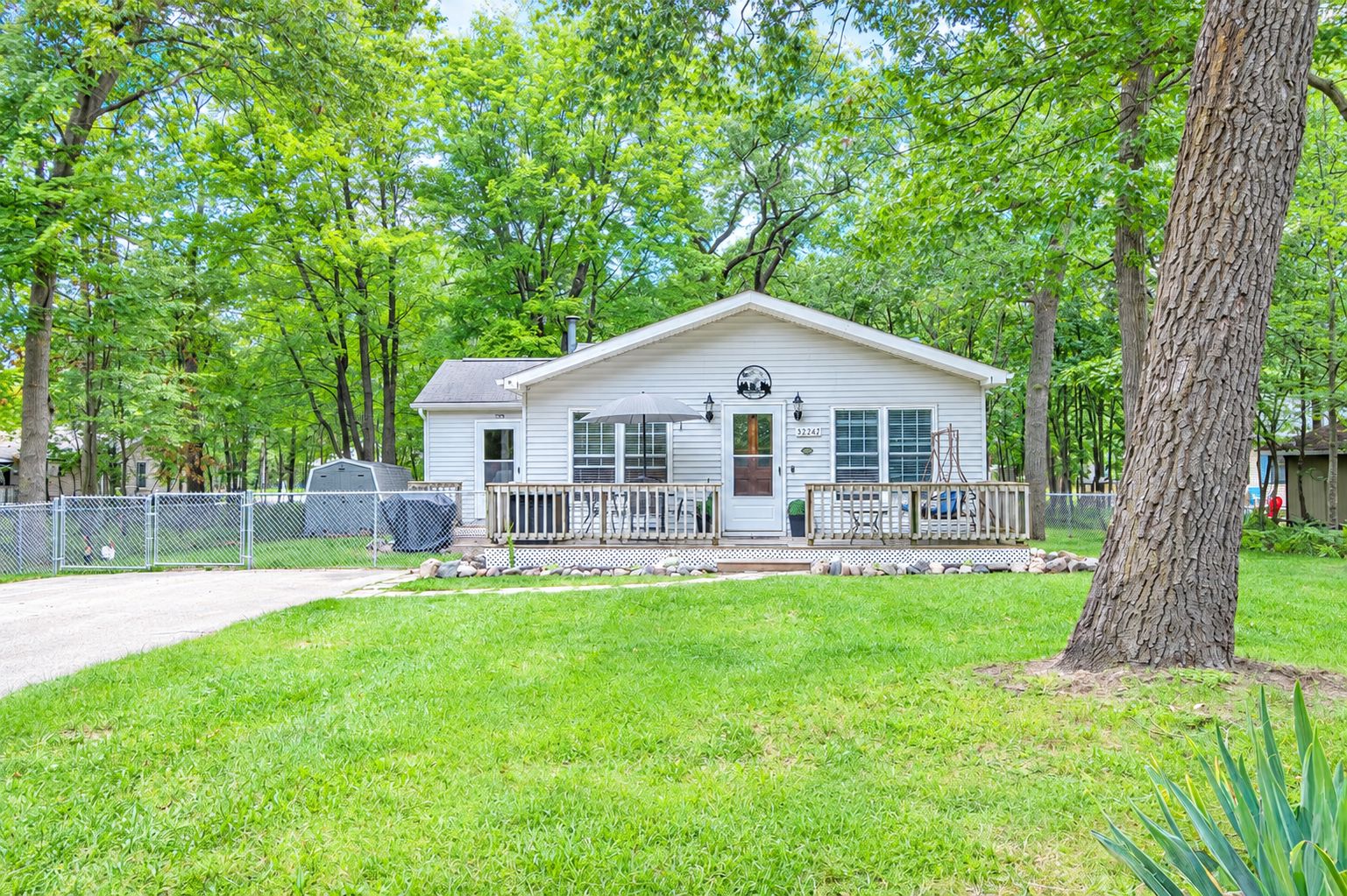A single-story house with a front porch, a fenced yard, and a mailbox.