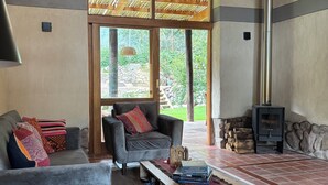 Un salon chaleureux avec une cheminée, des sièges confortables et une vue sur l’extérieur.