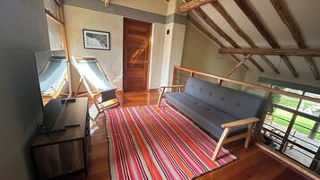 A room with a wooden ceiling, a sofa, a striped rug, and a door.