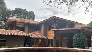Une maison à deux étages, avec un toit en tuiles, une piscine et un jardin.