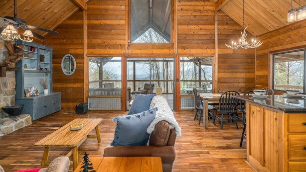 A spacious cabin with a high ceiling, wooden walls, a dining area, and a kitchen with large windows. - Ellijay Mountain View, Pets, Pool, Firepit, HotTub, Gameroom, Grill & Fireplace (Ellijay)