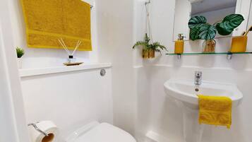 A bathroom with a white sink, a yellow towel, and a toilet.