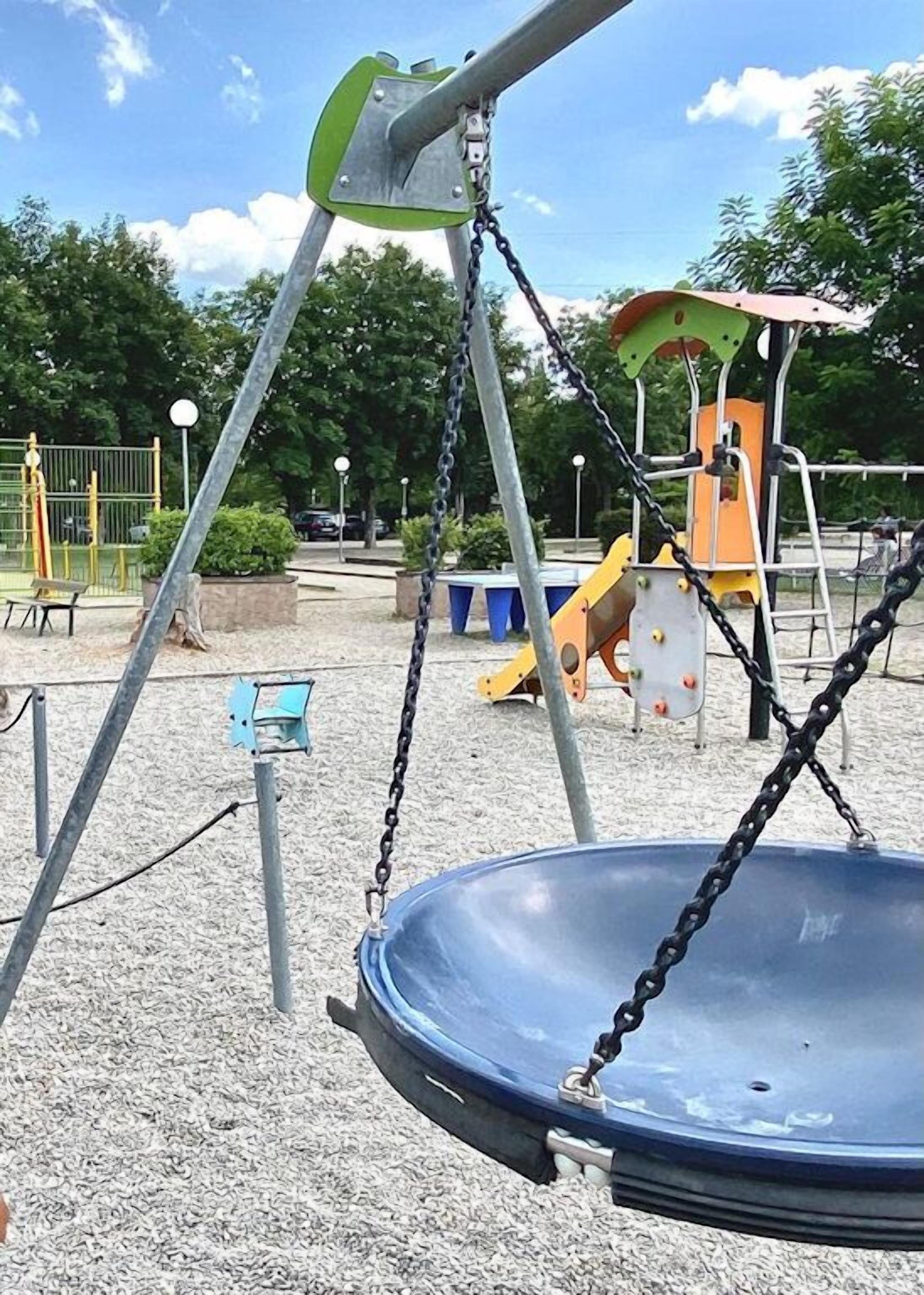 Ein Spielplatz mit Schaukel, Rutsche und Klettergerüst.