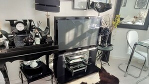 Un salon moderne doté d’un téléviseur à écran plat, d’une table basse et d’un coin repas avec une chaise.