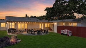 A covered patio area with outdoor furniture, a wooden fence, and a well-maintained lawn.
