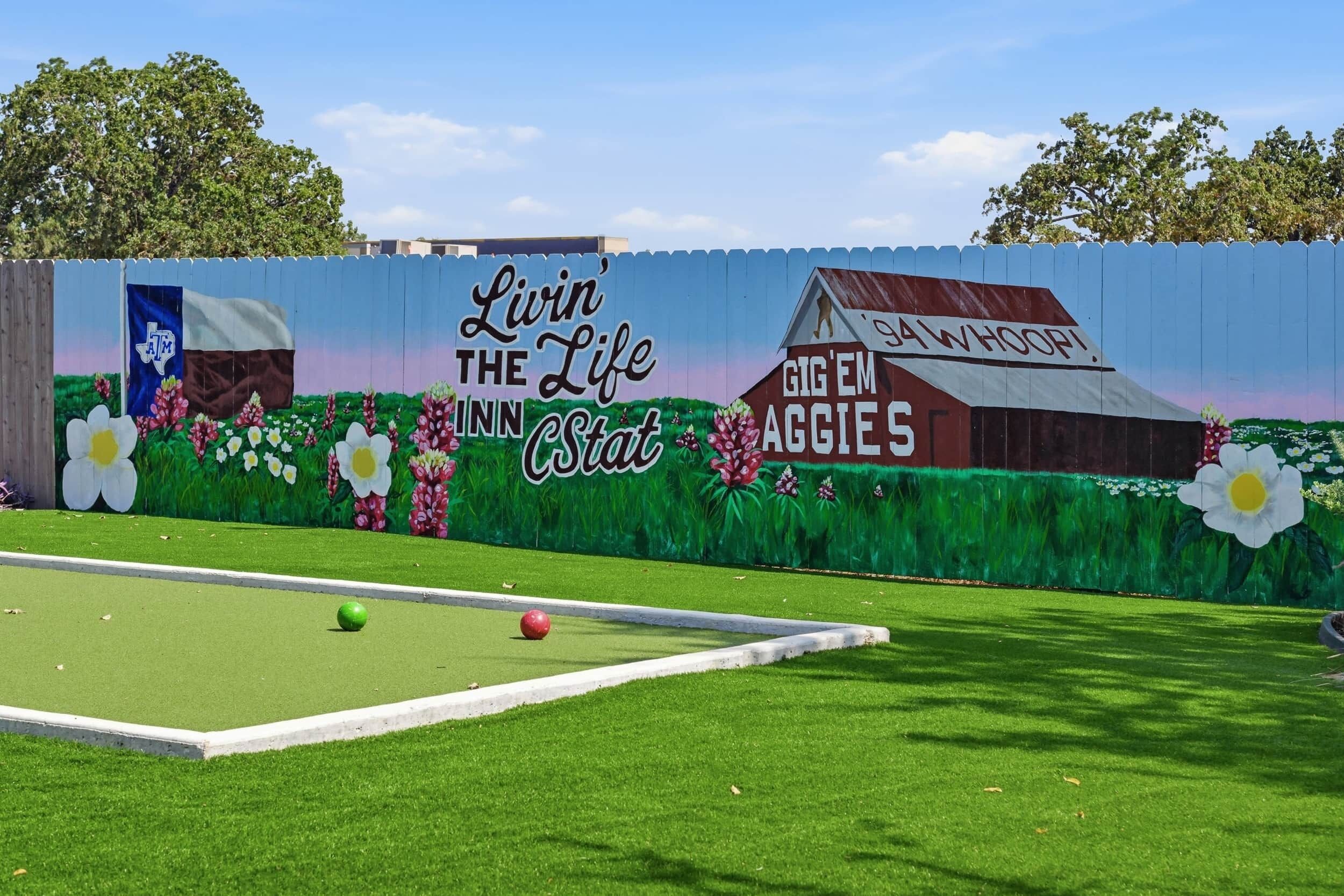Una pista da bowling con un murale pubblicitario di 'Livin' the Life Stat' e 'San Marcos Aggies'.