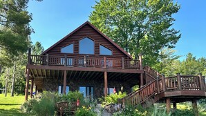 A large log cabin with a balcony and a wooden staircase leading to the entrance. - Spacious 5-bedroom lakefront house in charming Vulcan with WiFi, AC (Vulcan)