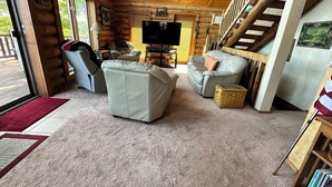 A log cabin interior with a living room featuring a sofa, armchair, and a television. - Spacious 5-bedroom lakefront house in charming Vulcan with WiFi, AC (Vulcan)